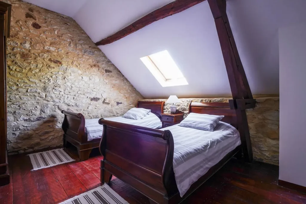 Chambre mansardée aux deux lits simples, éclairée par une fenêtre de toit