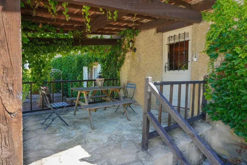 Terrasse ombragée par une treille, avec table et banc