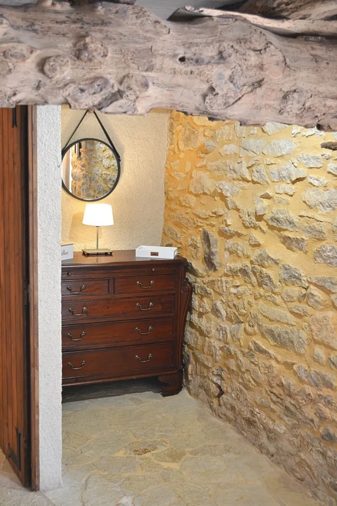 Commode ancienne et lampe de chevet contre le mur de pierre