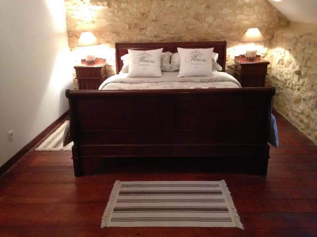Lit double en bois, lampes de chevet et tapis rayé sur le parquet