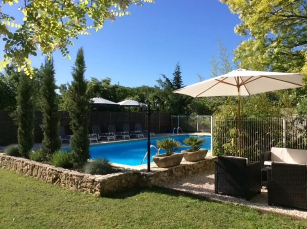 La piscine vue depuis le salon de jardin, entre cyprès et parasol