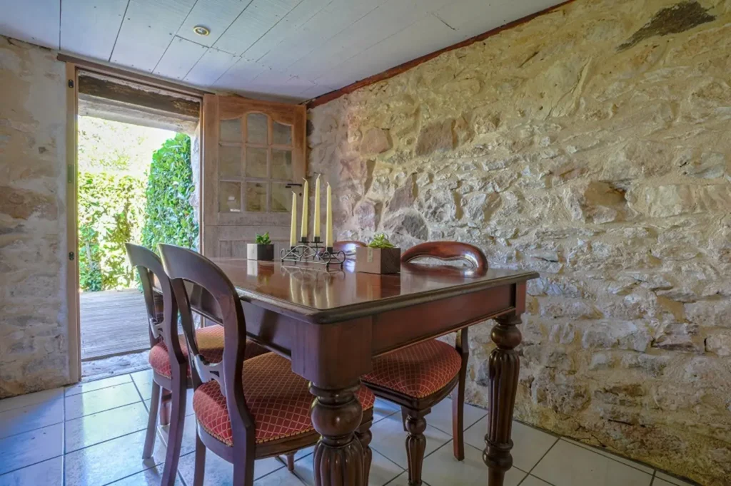 Table à manger en bois devant une porte ouverte sur le jardin