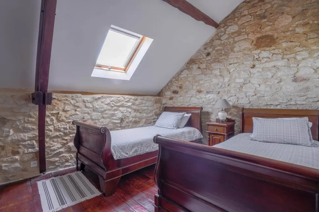 Chambre mansardée aux deux lits simples, éclairée par une fenêtre de toit