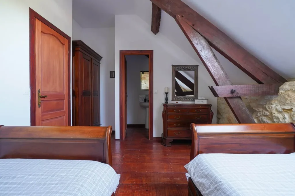 Chambre aux deux lits simples, armoire et commode en bois