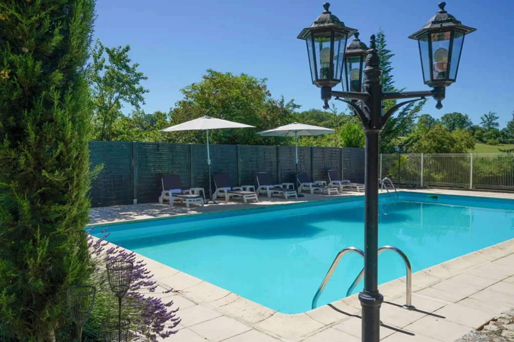 La piscine de la Maison Les Chandelles, bordée de transats et d'un lampadaire ancien
